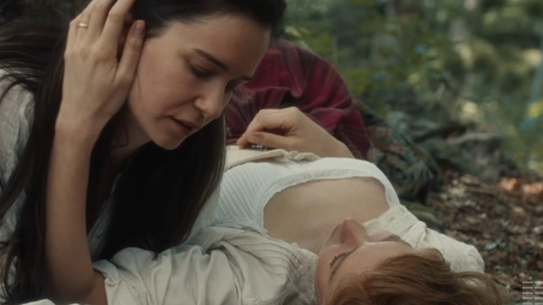 Vanessa Kirby as Tallie lying on the grass while Katherine Waterston as Abigail leans over her in The World to Come