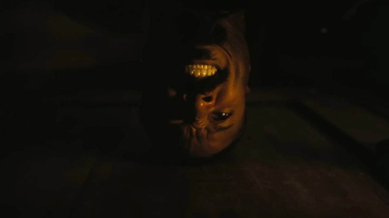 Stack (Michael B. Jordan) banging his head against the door and smiling in Sinners