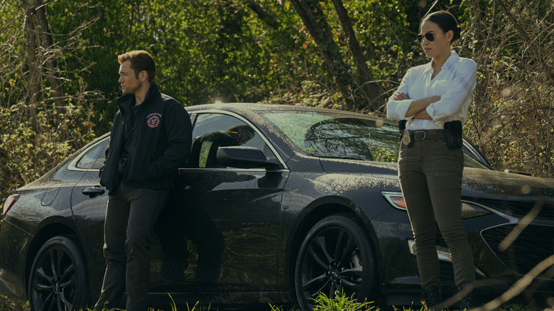 Dave and Michell standing by a car in the woods on Smoke